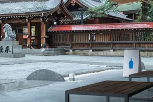 A serene Asian-style courtyard with stone and wood elements, featuring benches and a peaceful atmosphere