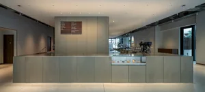 A modern restaurant interior with a counter and dining area featuring chairs and a display case with various food items