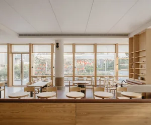 Empty restaurant interior with wooden floors and walls, featuring dining tables and chairs in a warm and inviting atmosphere