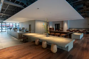 Warm and inviting restaurant space with wooden floors and walls, featuring dining tables and chairs, and potted plants