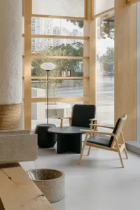Modern interior design showroom with minimalist decor, large windows, and natural light, featuring a dining table, chairs, and decorative elements