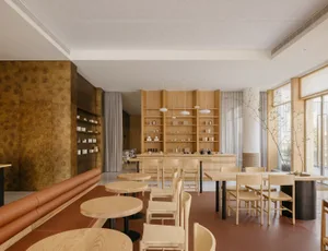 A spacious interior design showroom with wooden floors and walls, featuring tables, chairs, and decorative vases, with well-designed lighting creating a warm ambiance
