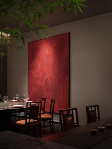 Warm and inviting dining area with a large red painting above a table, surrounded by multiple chairs