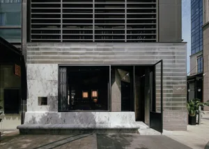 A modern restaurant entrance with a black doorway featuring a glass window, allowing natural light to enter, and comfortable seating for guests