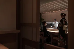 Cozy Asian restaurant interior with wooden tables, chairs, and a potted plant, featuring a comfortable and inviting atmosphere