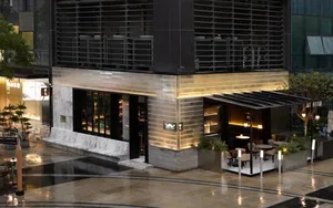 Modern exterior building scene with a large glass doorway, chairs, and inviting atmosphere