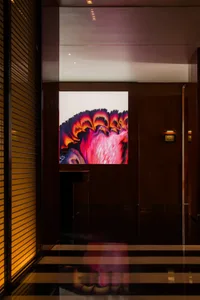 A room with a wooden floor and a large modern art painting on the wall, lit by artificial lighting