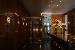 A sophisticated hallway with a marble floor, vases, and potted plants, creating a warm and inviting atmosphere