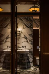 Bathroom with two sinks under a marble countertop, two toilets, and marble materials throughout