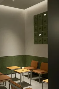 Modern showroom with two chairs in front of a wall displaying green M's, creating a welcoming atmosphere