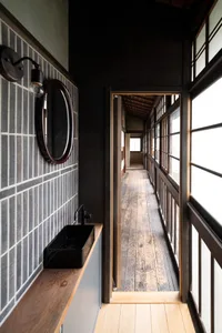 Narrow hallway with wooden floors and walls, featuring two sinks on either side, creating a dark and gloomy atmosphere