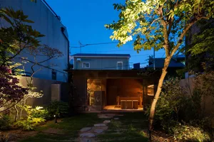A cozy outdoor dining space with two tables and chairs on a patio, illuminated by night lights