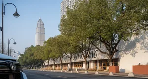 現代玻璃立面與白色外觀建築，周圍環繞樹木與繁華都市氛圍