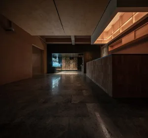 Dimly lit restaurant with a wooden bar, chairs, and a cozy atmosphere
