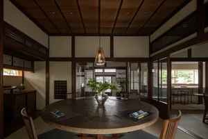 Warm and inviting dining space with a wooden table, chairs, and a vase, set in a cozy atmosphere