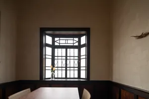 Empty dining room with a wooden table and chairs in front of a window, giving a warm and cozy atmosphere