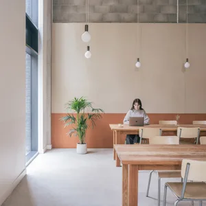 A restaurant interior with wooden tables and chairs, creating a warm and inviting atmosphere for guests to gather and enjoy their meals