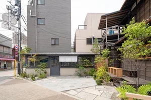 A city scene with a brick building and a modern building next to each other, featuring balconies and potted plants