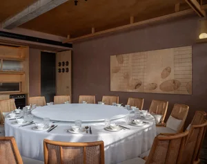 A round dining table surrounded by chairs in a warm and inviting atmosphere, set for guests with several cups on the table