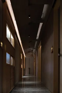 Dimly lit hallway with wooden doors, wooden walls, and natural light from two windows
