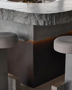 Modern living space with gray stools and a large industrial-style concrete table, set in a contemporary environment