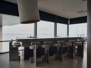 Bright and inviting kitchen with a modern design, featuring a large island countertop with stools and a sink, and natural light coming in through windows