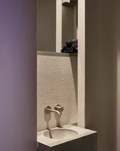 Modern bathroom with a wall-mounted sink, two faucets, and towels hanging nearby