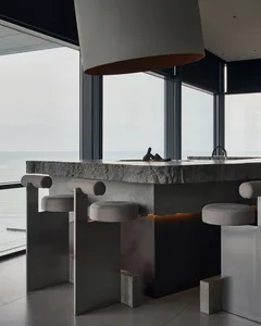 Modern kitchen with a large island countertop, stools, chairs, sink, and dining table, featuring a comfortable and inviting atmosphere