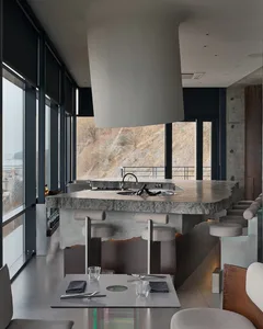 Open modern kitchen and dining area with a large island countertop, wine glasses, and comfortable seating for entertaining guests