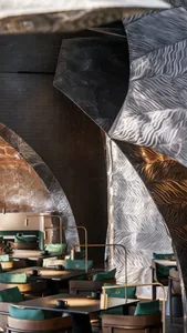 Modern restaurant interior with metallic walls, chairs, and tables, creating a sleek and inviting atmosphere