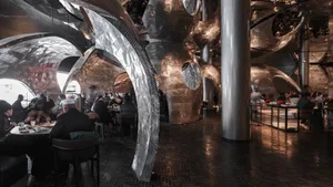 A modern restaurant interior with tables, chairs, and a sophisticated atmosphere, featuring a stylish dining space for guests to socialize and dine