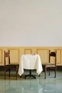 An empty dining area with two chairs around a white tablecloth, creating a calm and serene atmosphere
