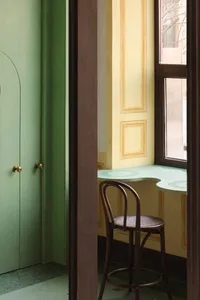 Small room with green walls, yellow trim, two chairs, and a window providing natural light