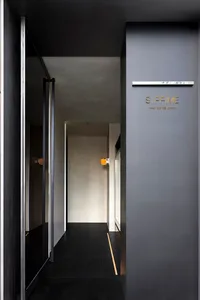 現代酒店走廊擁有混凝土牆面、兩扇開啟的門，以及黃色燈光為空間增添溫暖氛圍