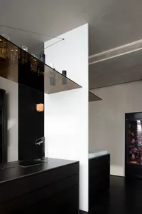 Modern kitchen with black cabinets, a sink, and dining area with a table and chairs, wine glasses, and a sleek design
