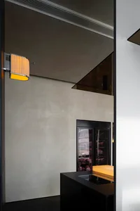 A modern dining area with a table and chairs, part of a larger space with a kitchen and refrigerator in the background