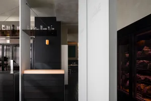 A modern kitchen with a dining area, featuring a countertop with a sink, cabinets, and decorative items, surrounded by chairs and a dining table