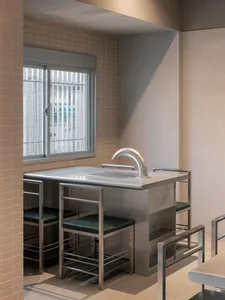 Empty bathroom with a metal sink and a window, two chairs, and natural light