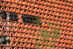 A modern building with a red brick exterior, numerous small windows, and a focus on natural light