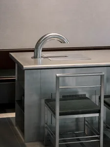 Modern kitchen dining space with a metal sink and wooden dining table, two chairs, and a sleek design