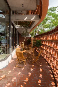 A casual outdoor dining area with wooden chairs and glass-topped tables, surrounded by a pleasant atmosphere
