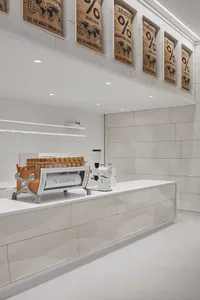 A coffee shop interior with a counter featuring two espresso machines, cups, and a bowl, set in a clean and organized atmosphere