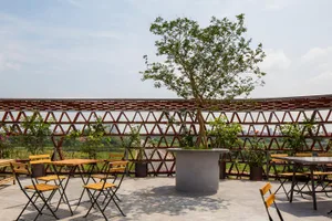 A relaxed outdoor patio area with stone tables, umbrellas, and potted plants, perfect for dining or conversation