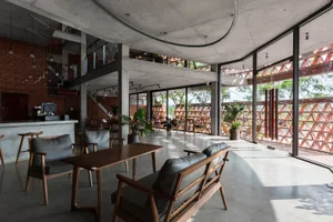 Open living space with a hardwood floor, a large couch, dining table, chairs, and potted plants, creating a comfortable and inviting atmosphere