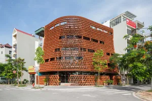 一座現代建築，設計成書櫃造型，擁有各種窗戶與混凝土外牆，背景為晴朗白天的景觀