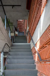 現代多層建築，配有樓梯與中性色調，混凝土與金屬結構，自然光線營造寧靜氛圍