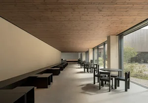 Inviting restaurant with wooden floors and walls, tables, chairs, and natural light from windows