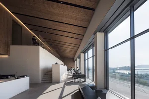 Spacious modern lobby with high ceilings, wooden elements, and people socializing around chairs and dining tables