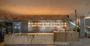 A cozy bar area with a wooden counter featuring numerous bottles of alcohol and two cups, creating a warm and inviting atmosphere