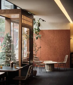 Modern restaurant interior with a dining area, bar counter, and potted plants, featuring red brick walls and a warm atmosphere